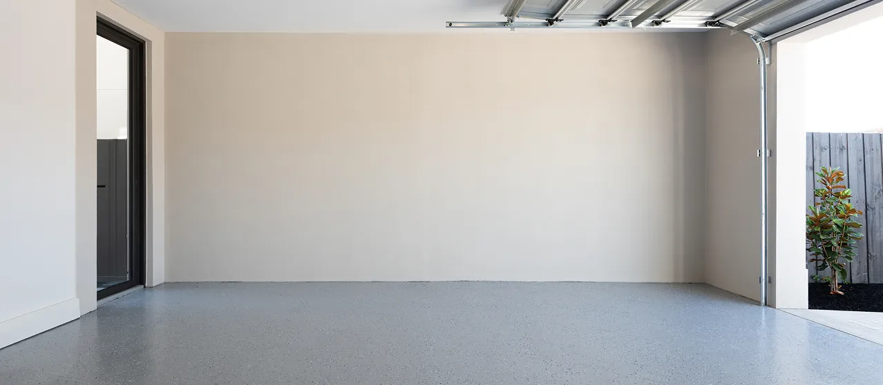 Garage vide aux murs blancs et au sol en béton, assaini contre l’humidité